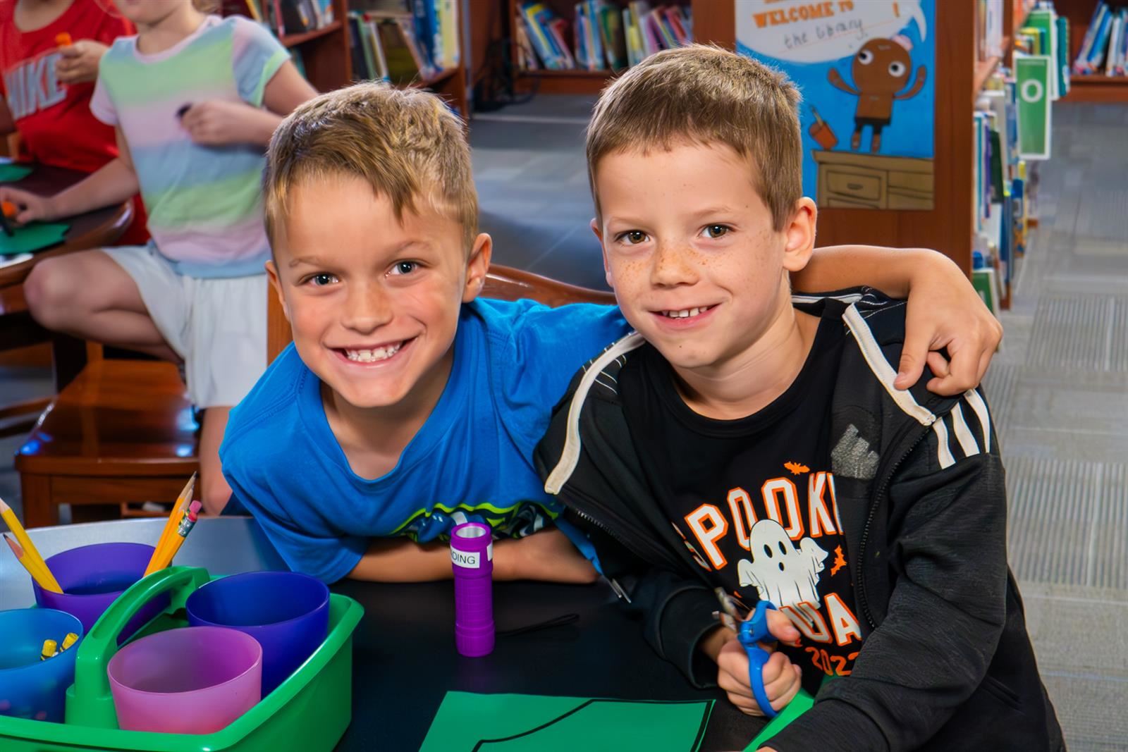 two boys smiling at desk